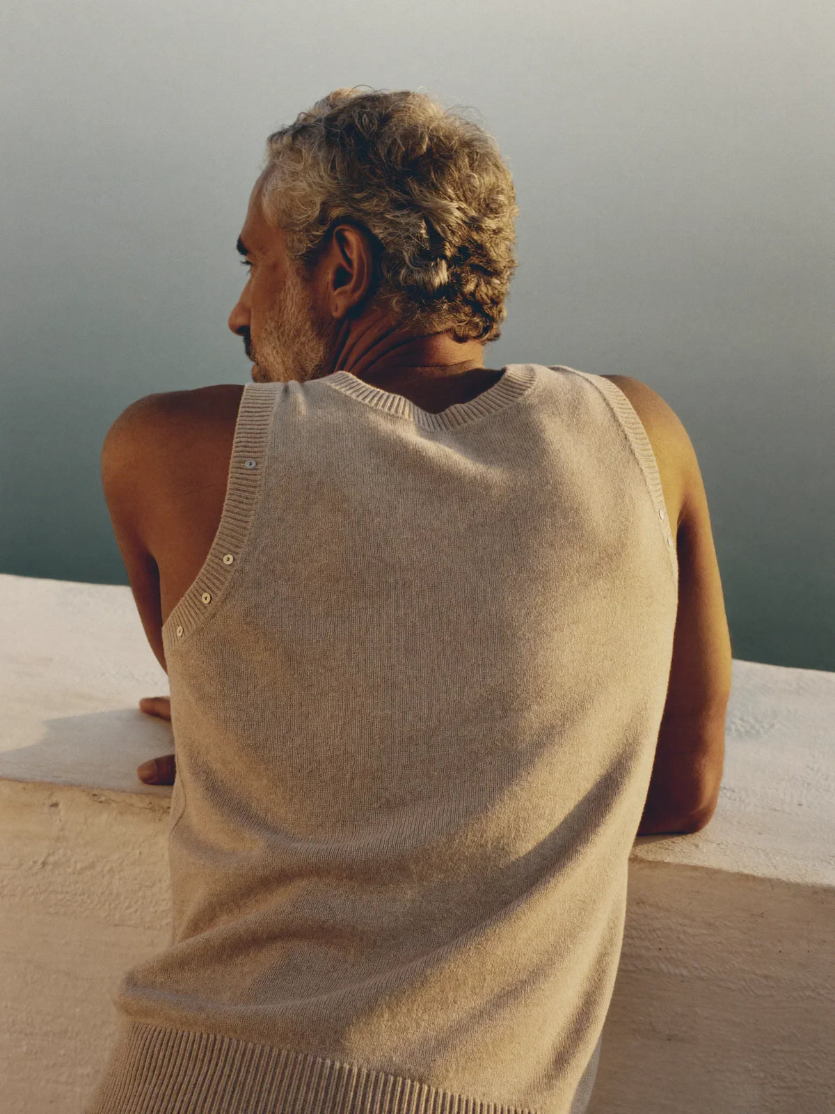 Man in an oatmeal cashmere sweater in a sunlit Greek lane